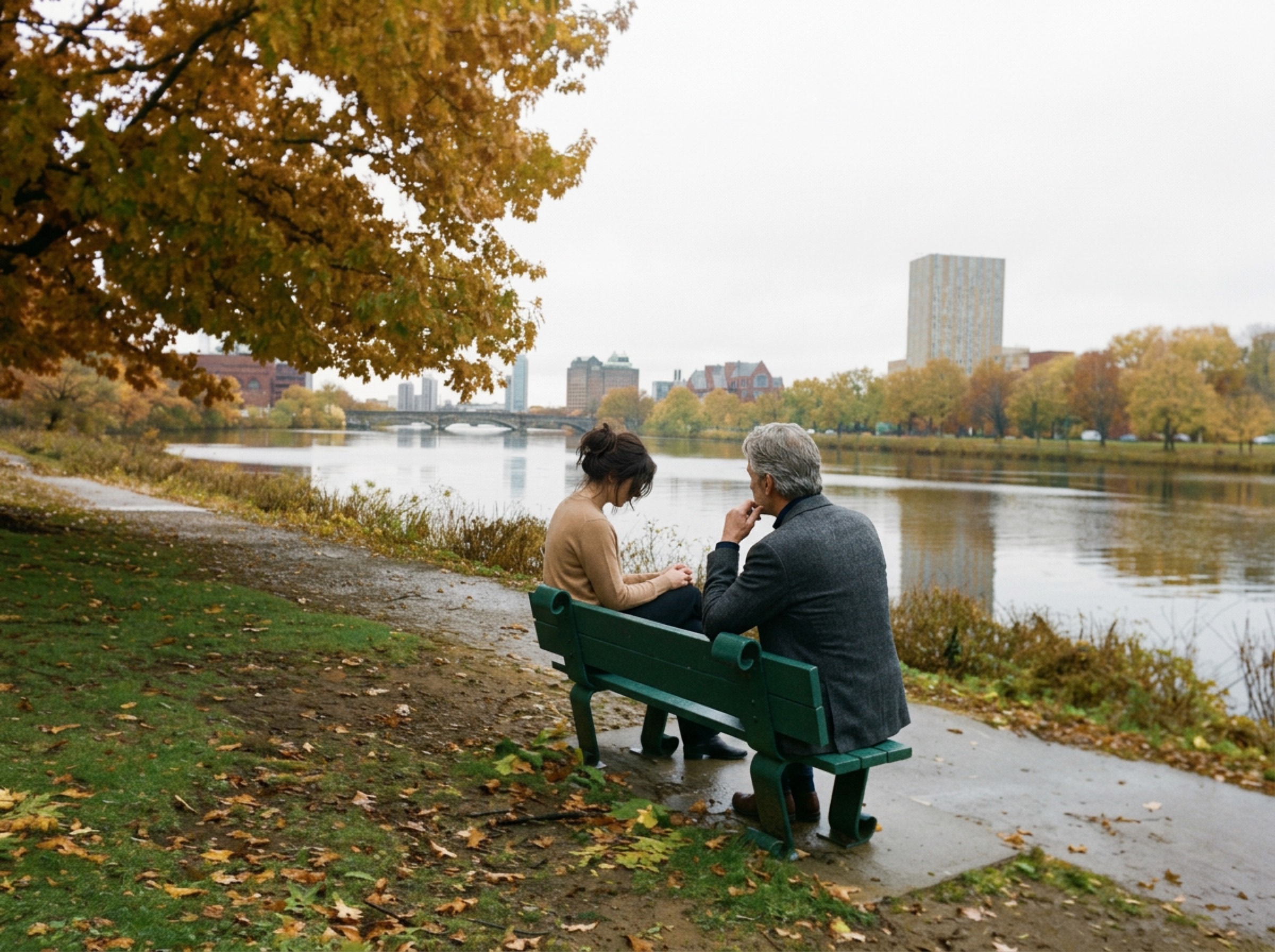 Two people talking on a bench by the Charles River in autumn